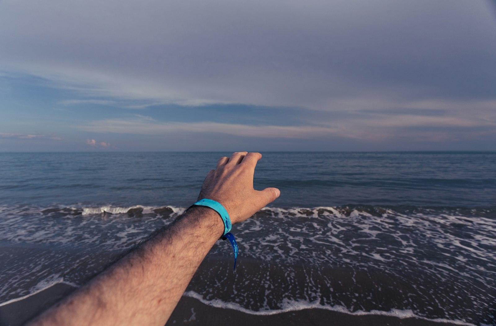 Bare arm reaching into bright sunlight by the sea, the kind of sudden sun exposure that triggers polymorphic light eruption