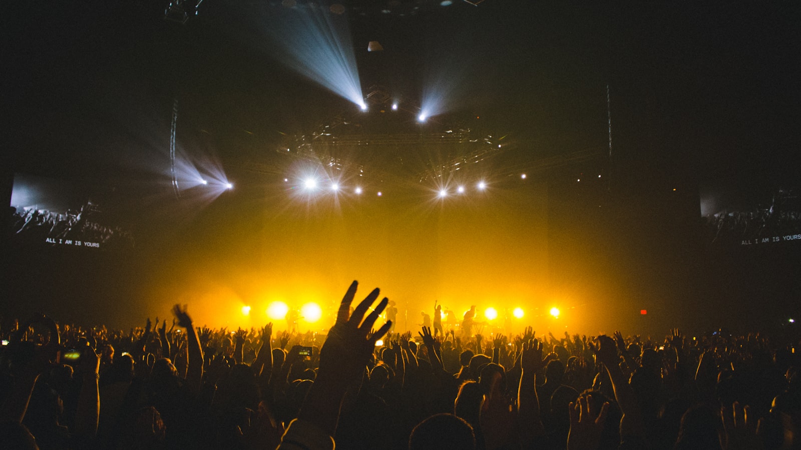 Festival crowd with raised hands in front of a main stage at night