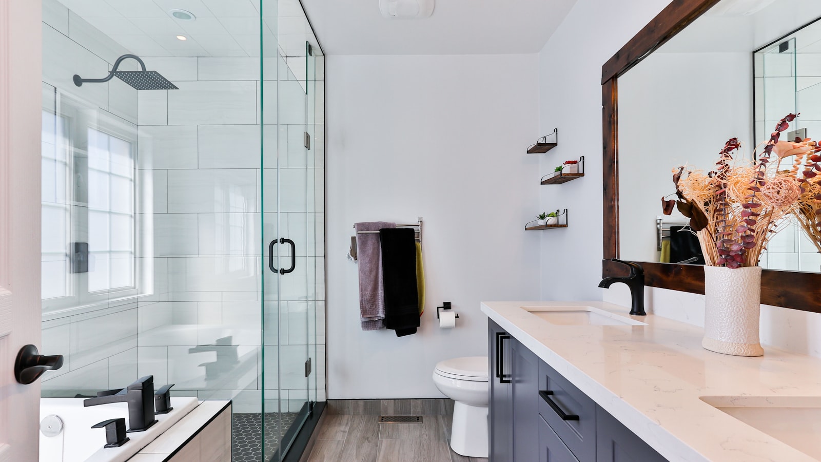 Bathroom wall with slim open shelves, towel rail and vanity drawers making use of vertical space