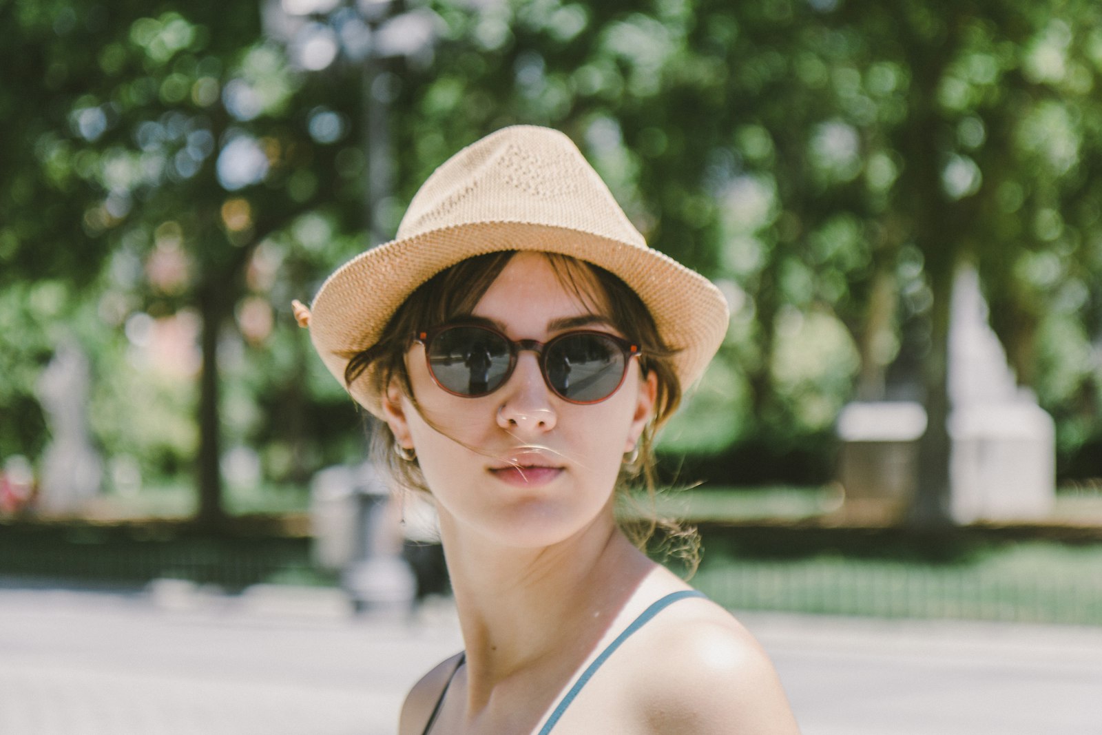 Woman wearing a wide-brimmed hat and sunglasses in summer sunshine