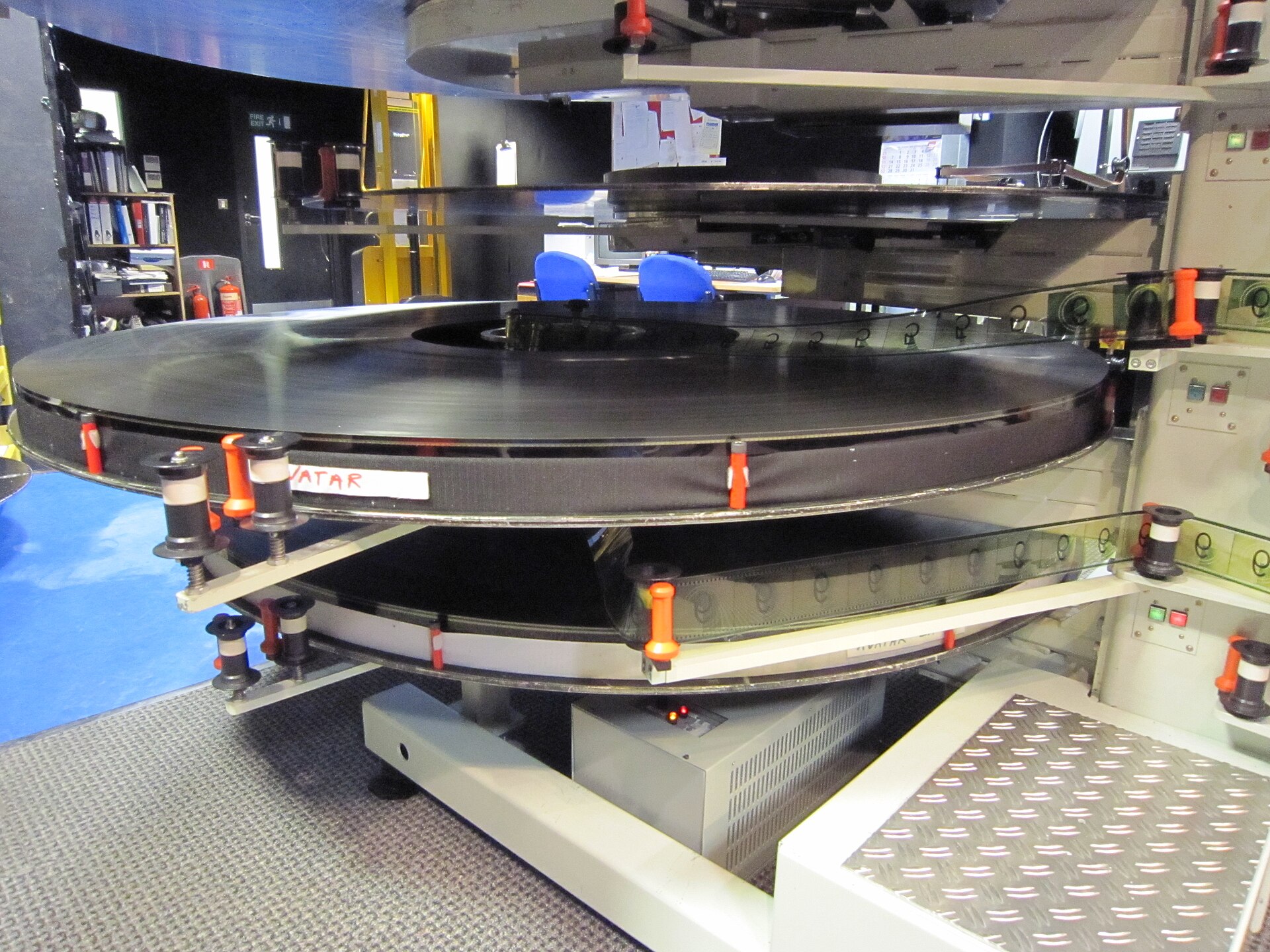 Reels of 70mm film stacked beside an IMAX projector