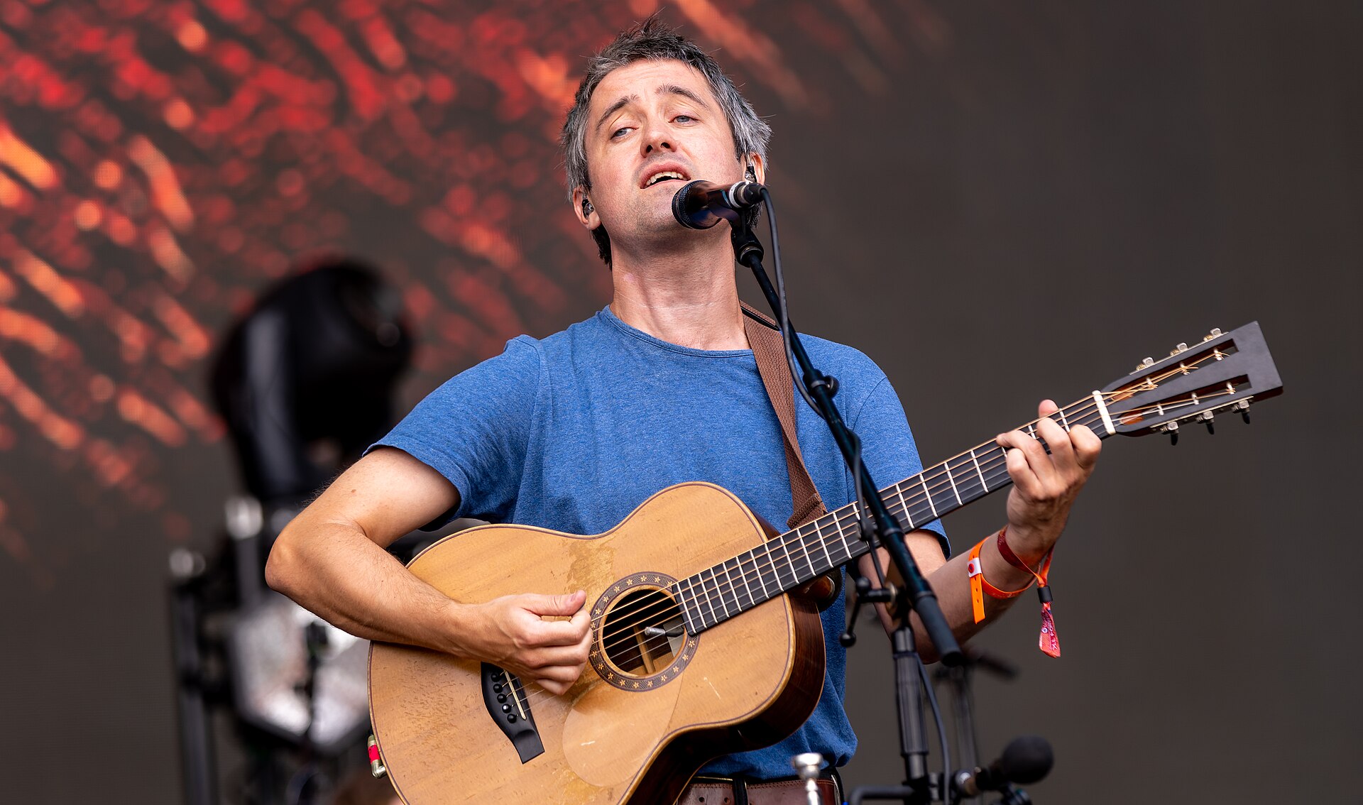 A singer with an acoustic guitar performing in daylight at All Points East in Victoria Park