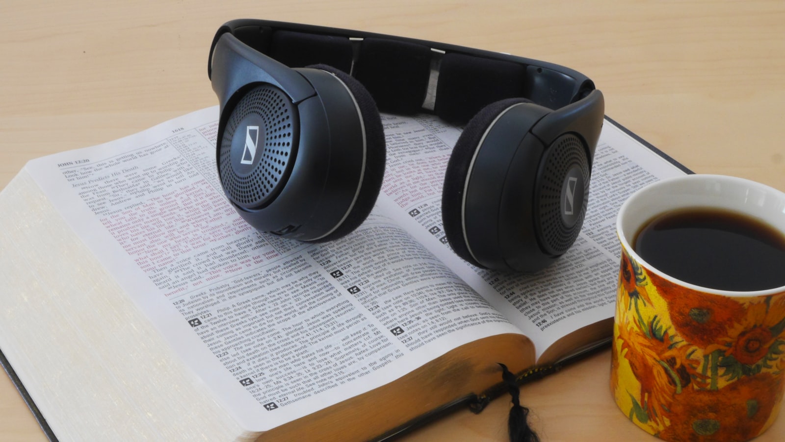 Headphones resting on an open book beside a cup of coffee - the best British audiobooks 2026 travel well