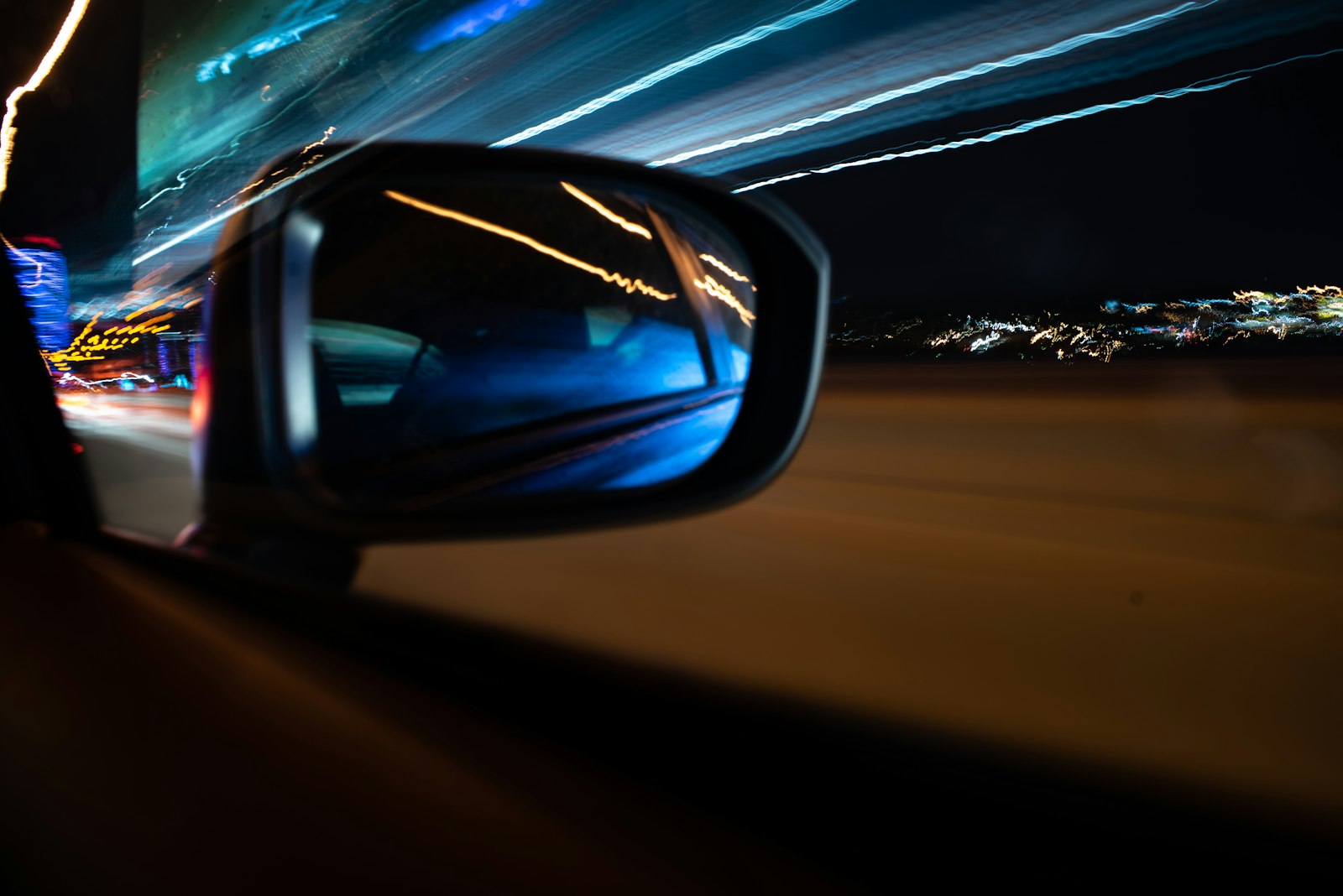 Motorway traffic seen through a car side mirror on a long drive