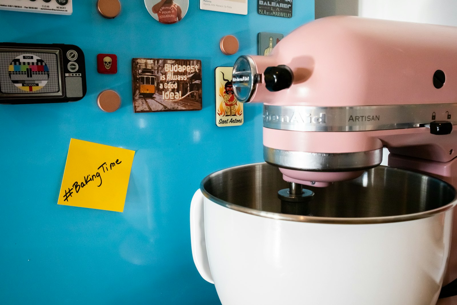 A pastel retro stand mixer in front of a blue wall