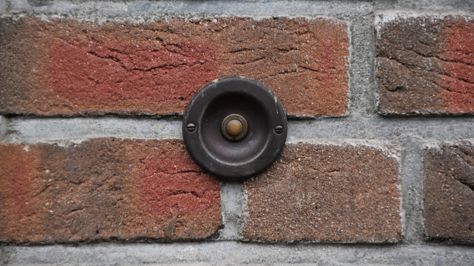 Best video doorbell under £100 mounted on a red brick wall beside a front door