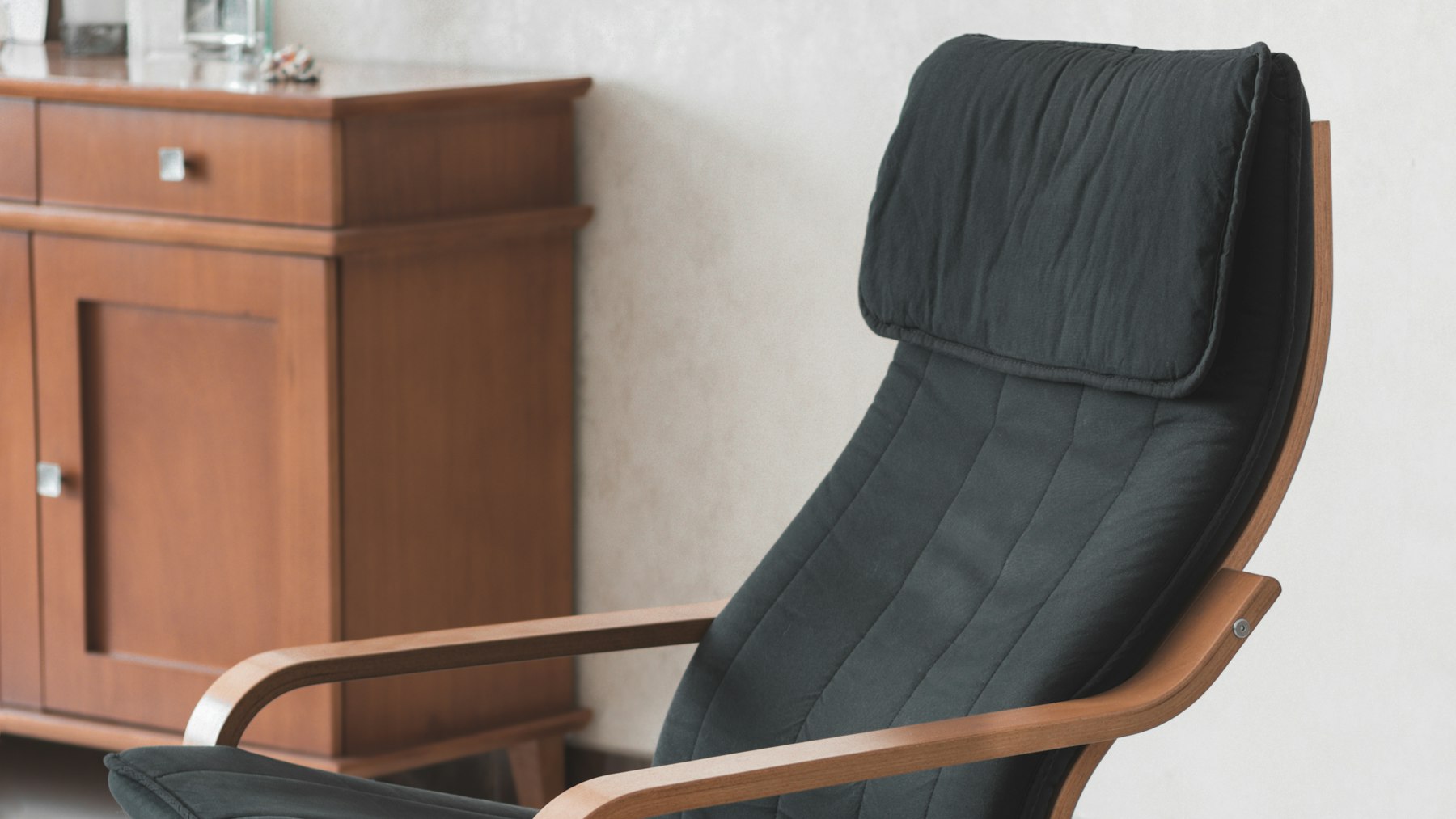 Antique wooden armchair with dark upholstery against a plain wall