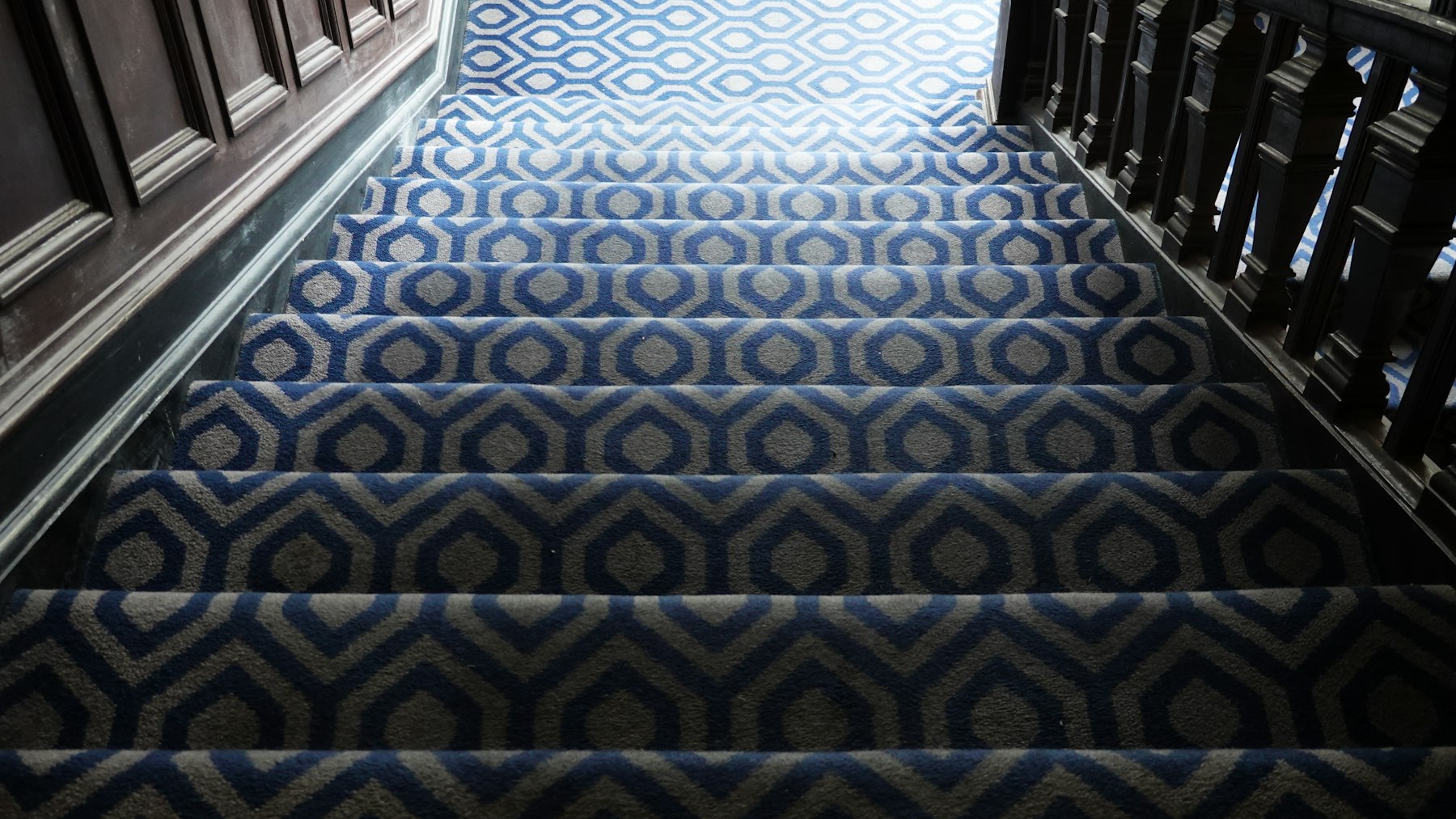 Patterned blue and cream stair carpet with dark wooden banisters, the staircase look at the heart of carpet trends 2026