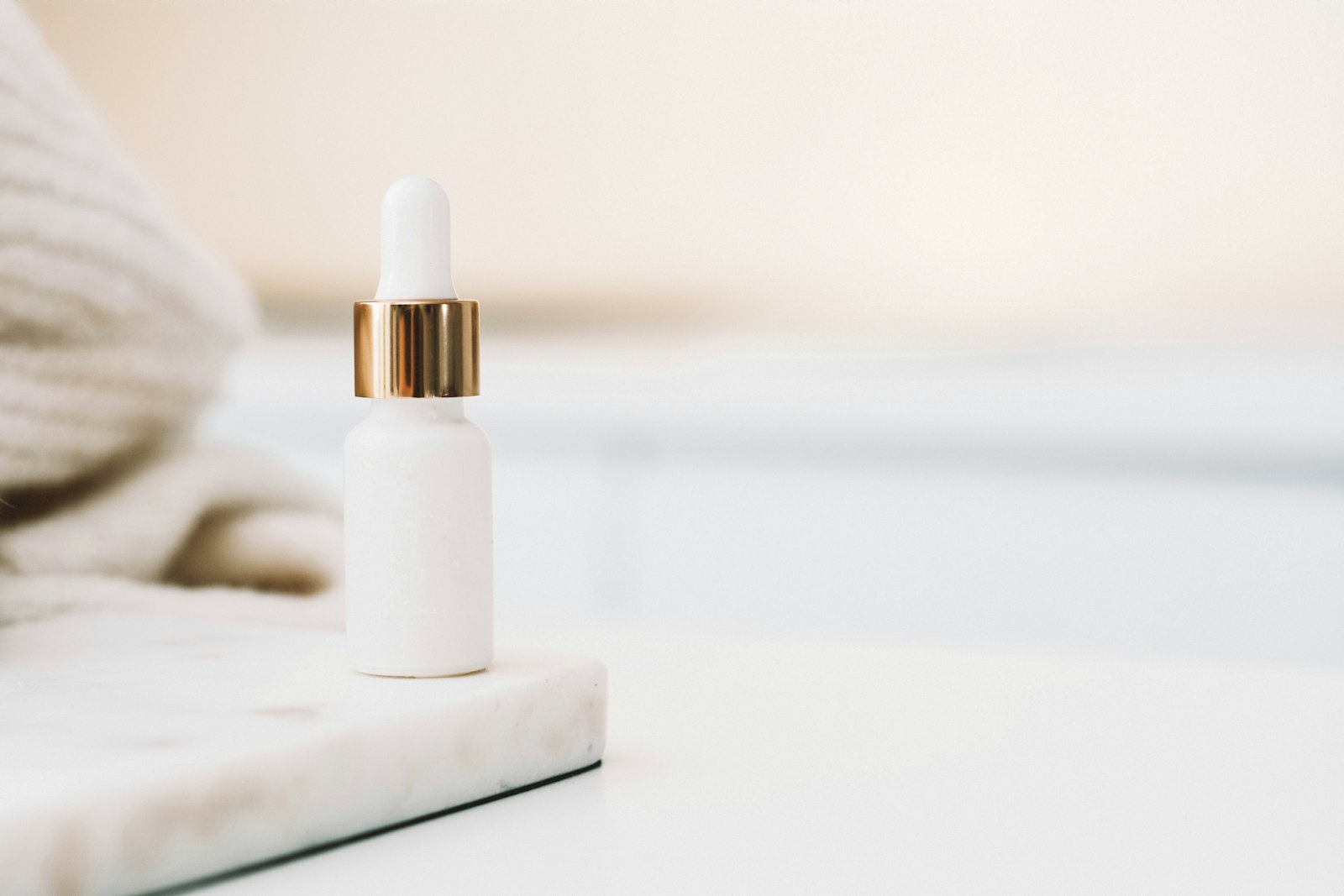 Minimalist white dropper bottle of soothing essence on a marble tray
