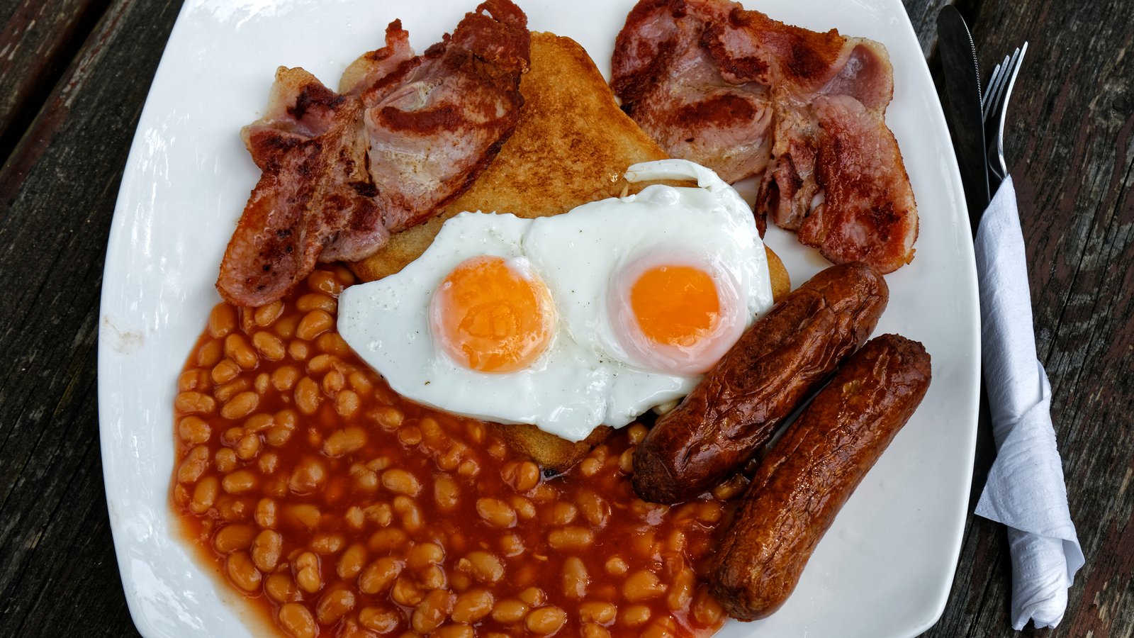 A full English breakfast on a cafe plate - eggs, bacon and beans cover how much protein you actually need at breakfast without any fortified products