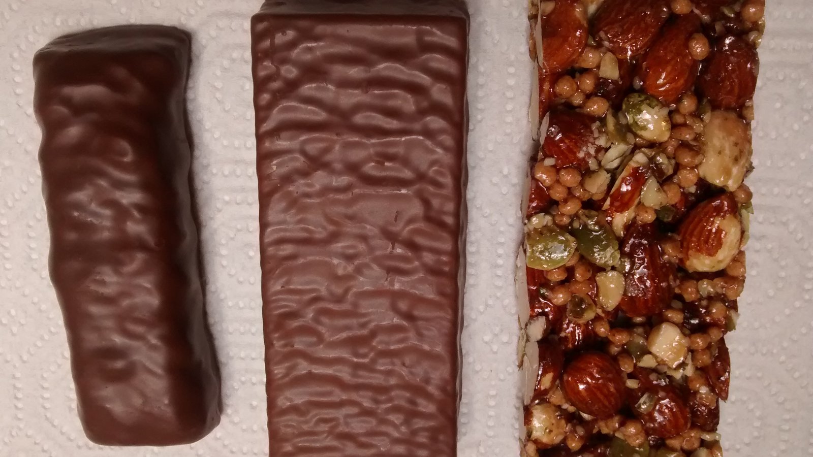 Three wrapped protein bars laid side by side on a plain surface