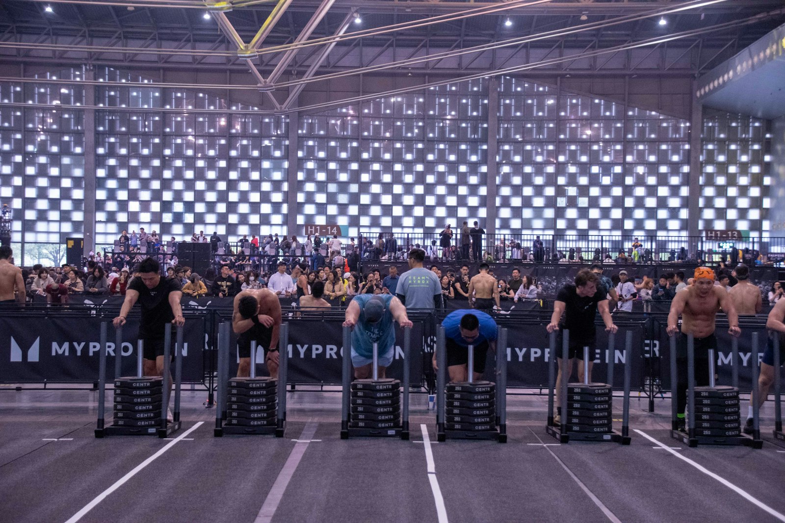 Competitors pushing weighted sleds indoors - the station every Hyrox for beginners plan obsesses over