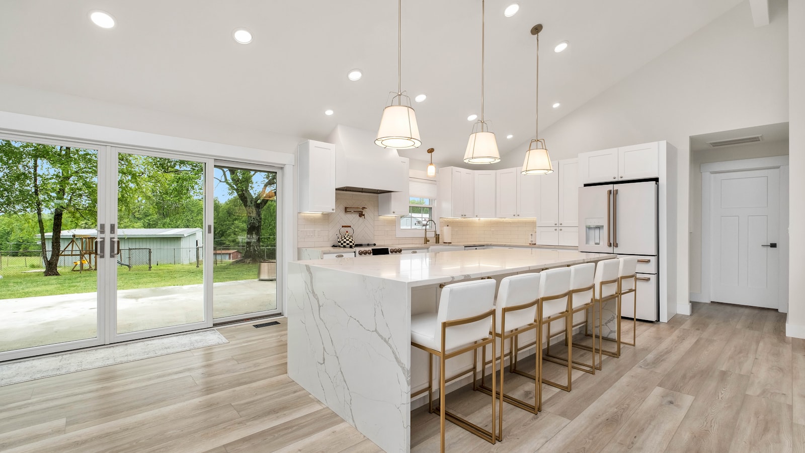 Large fitted kitchen island with a marble worktop in a modern open plan kitchen