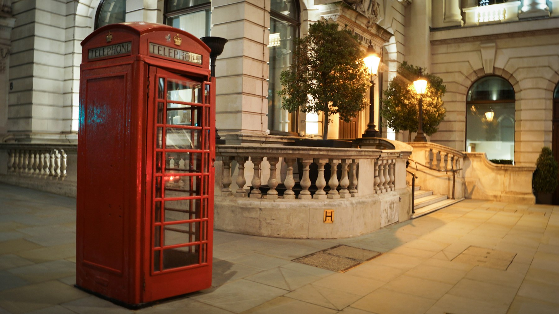A red telephone box beside green trees - the analogue phone era bowing out