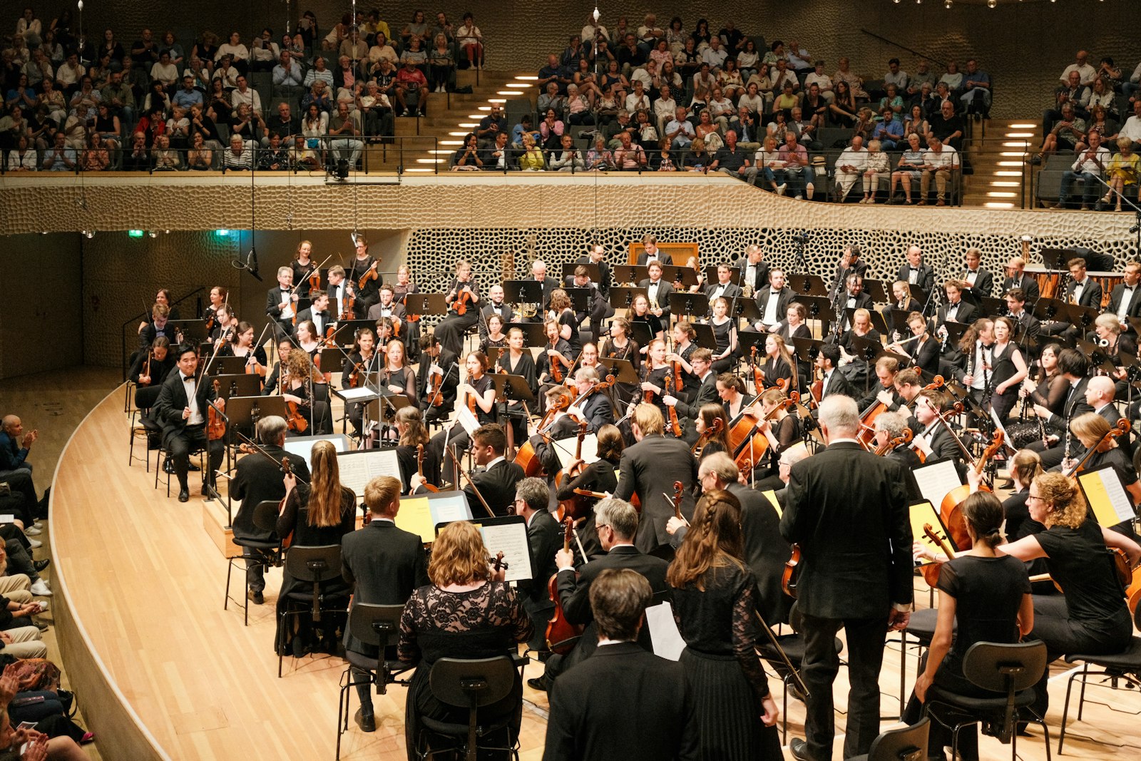 A conductor leads a full orchestra in a concert hall