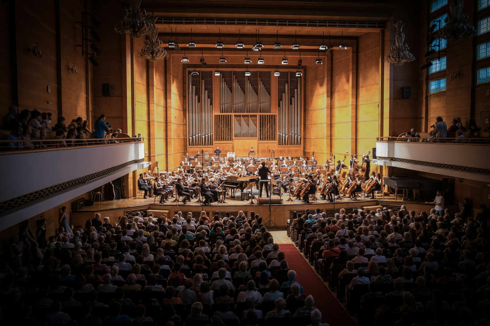 Audience watching an orchestra perform under warm stage lighting