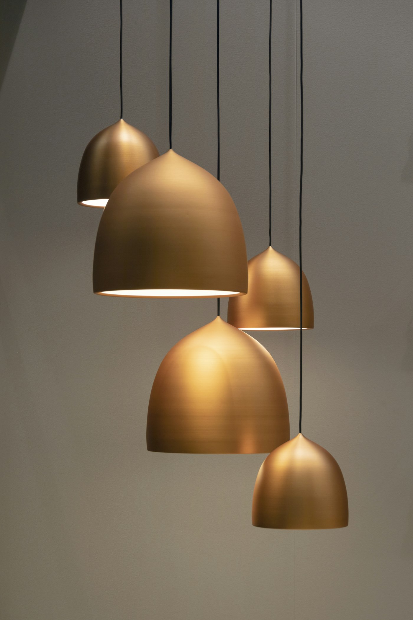 Cluster of brushed brass pendant lights glowing warm