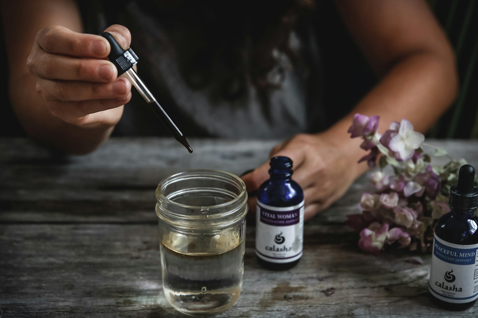Fresh herbs steeping in a glass jar of water, the traditional preparations these tinctures are based on