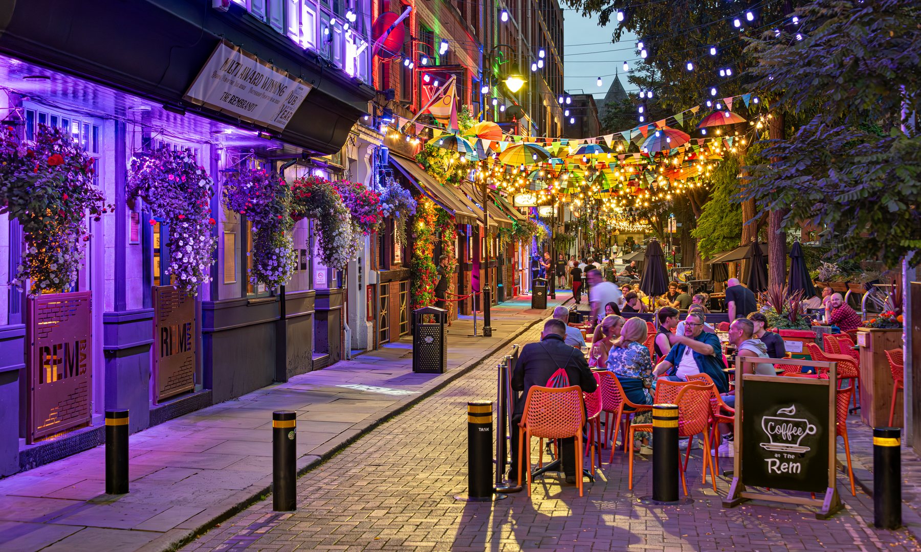 Canal Street in Manchester's Gay Village at dusk, dressed with lights and umbrellas for Manchester Pride 2026