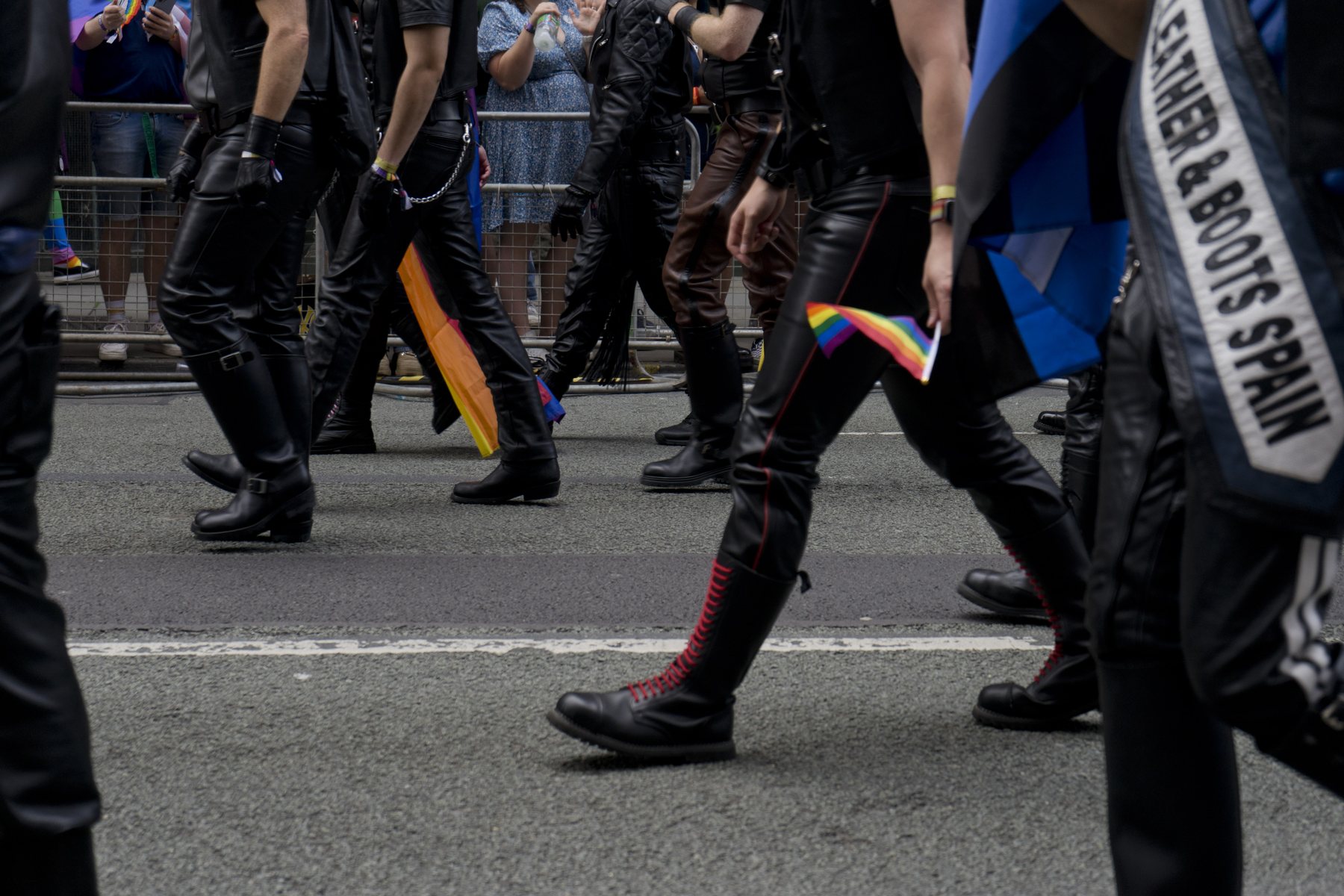 Marchers carrying rainbow flags past crowd barriers in the Manchester Pride parade