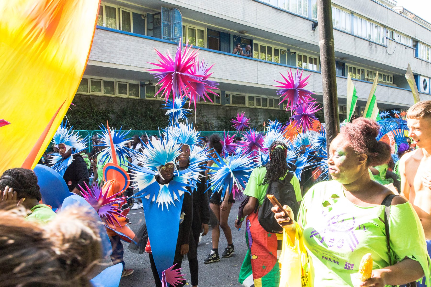 Children's Day mas band in blue and pink starburst costumes passing spectators on the carnival route