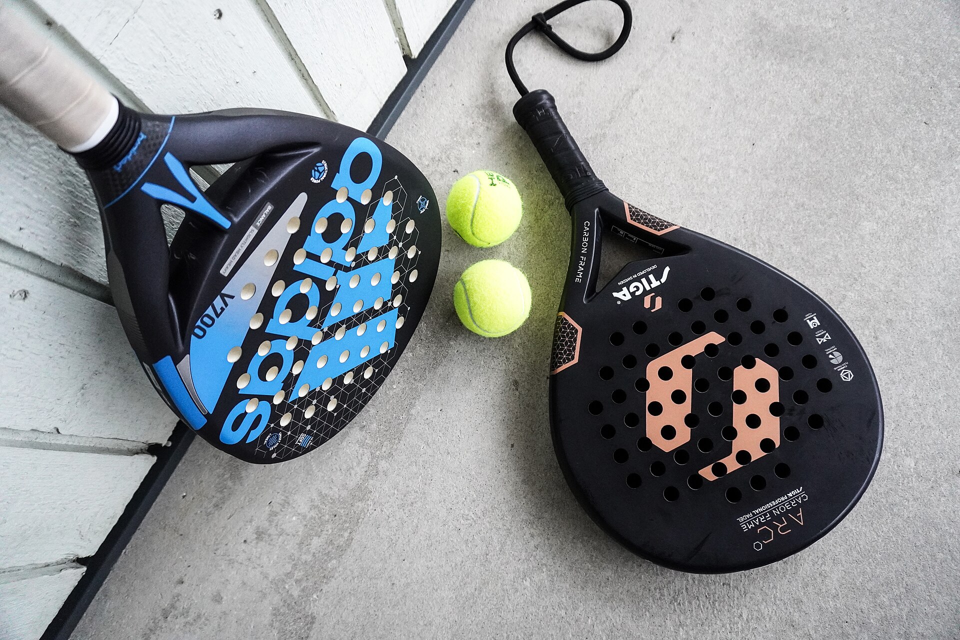 Two padel rackets and balls on a court surface, the kit behind most padel injuries in 2026