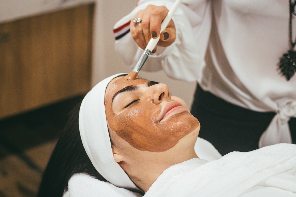 Woman receiving a facial treatment with a mask applied by brush