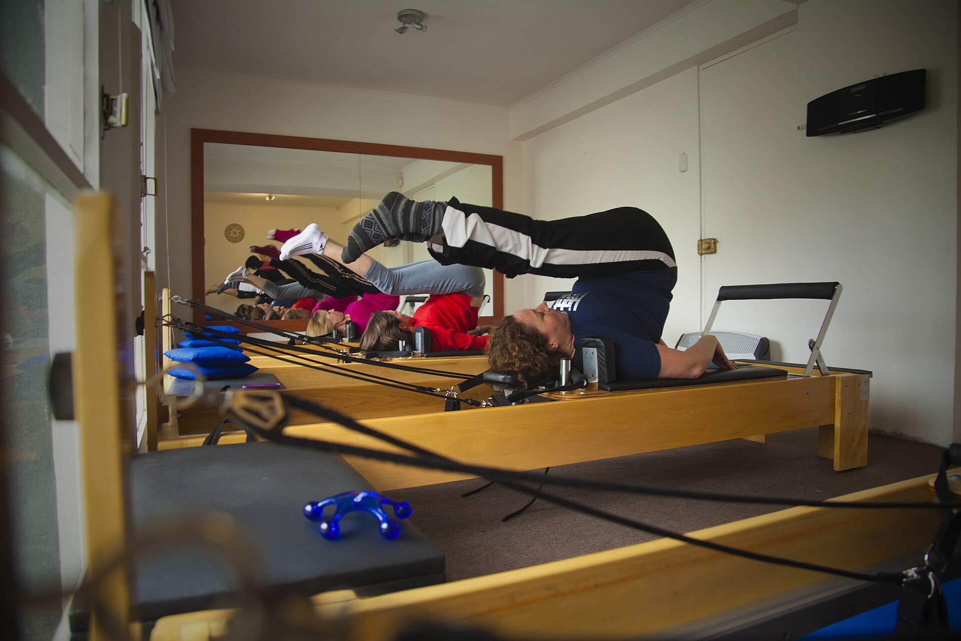 A group class practising shoulder bridge variations together on reformer machines
