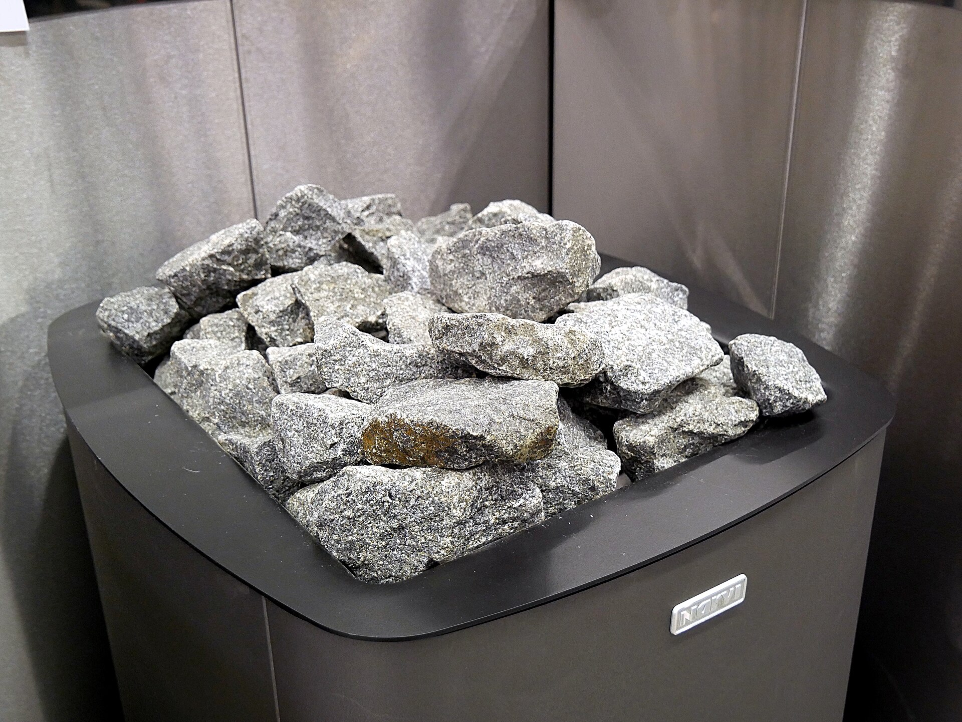 Water being ladled over hot sauna stones on a heater