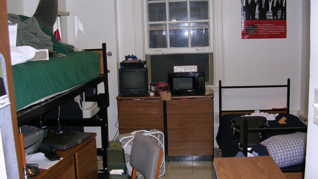 Uni room essentials in a typical student halls bedroom with bed, desk and storage