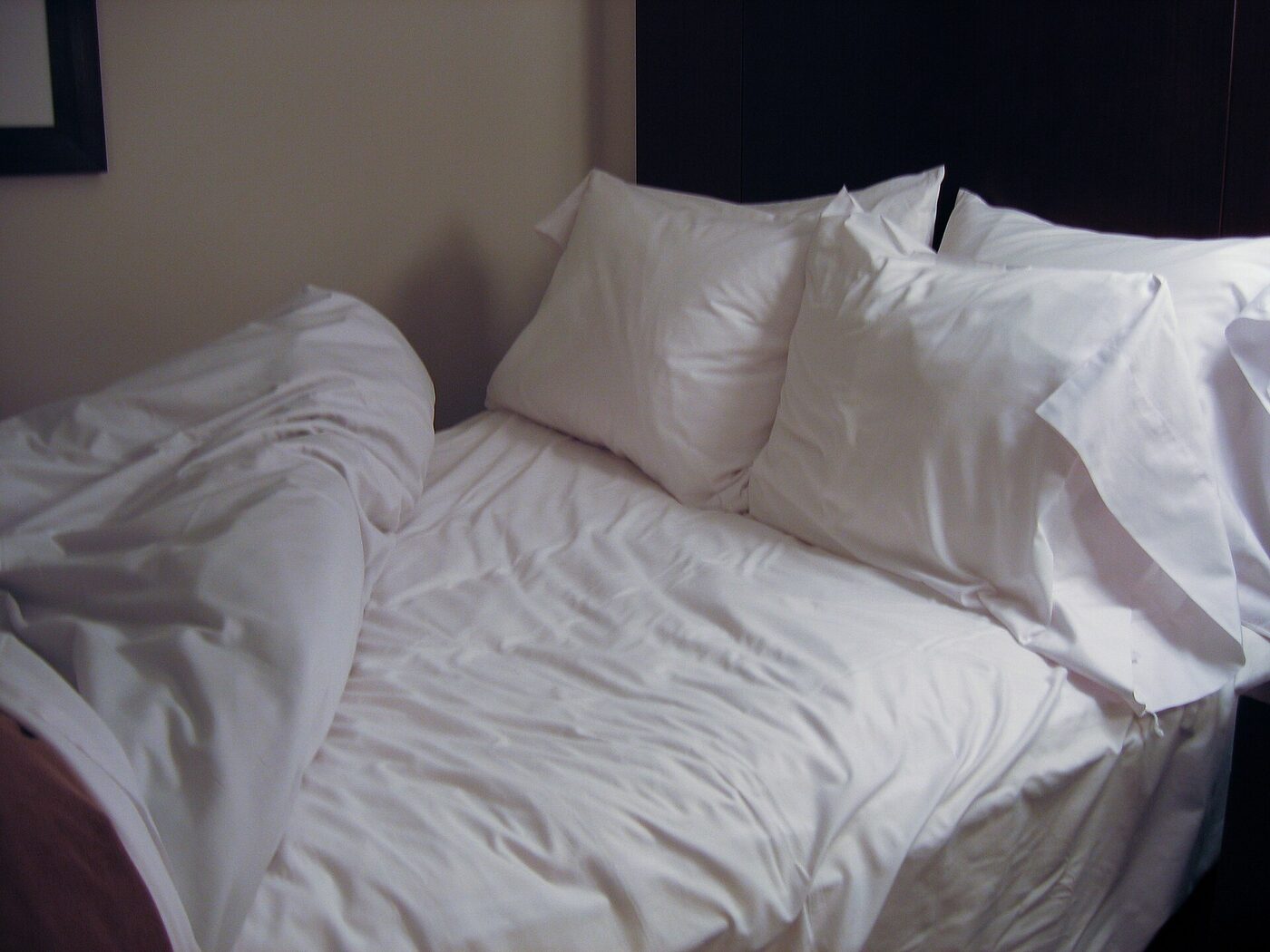 White duvet and pillows on a single bed with a mattress topper