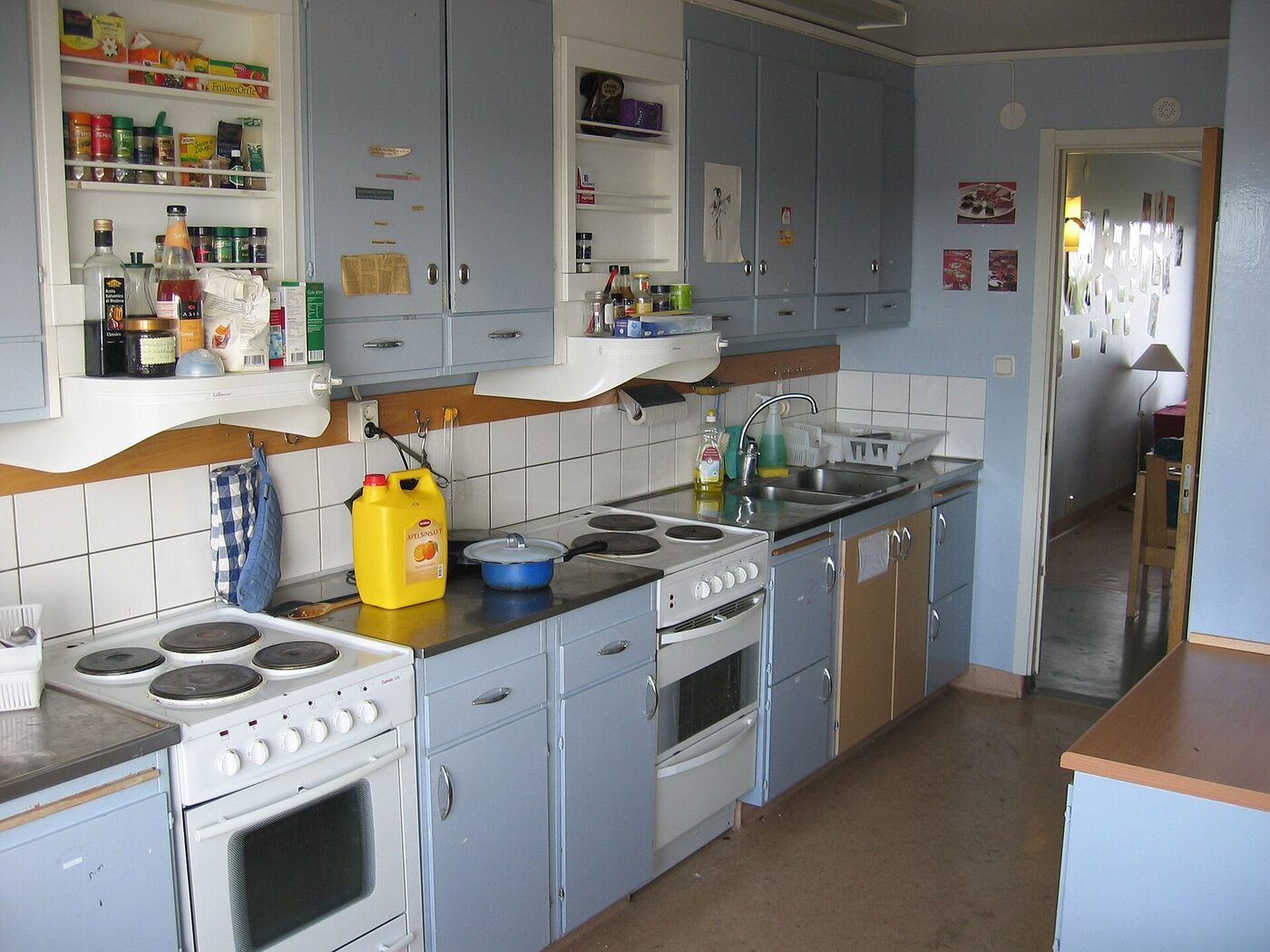 Shared student kitchen with cookers, pans and cluttered shelves
