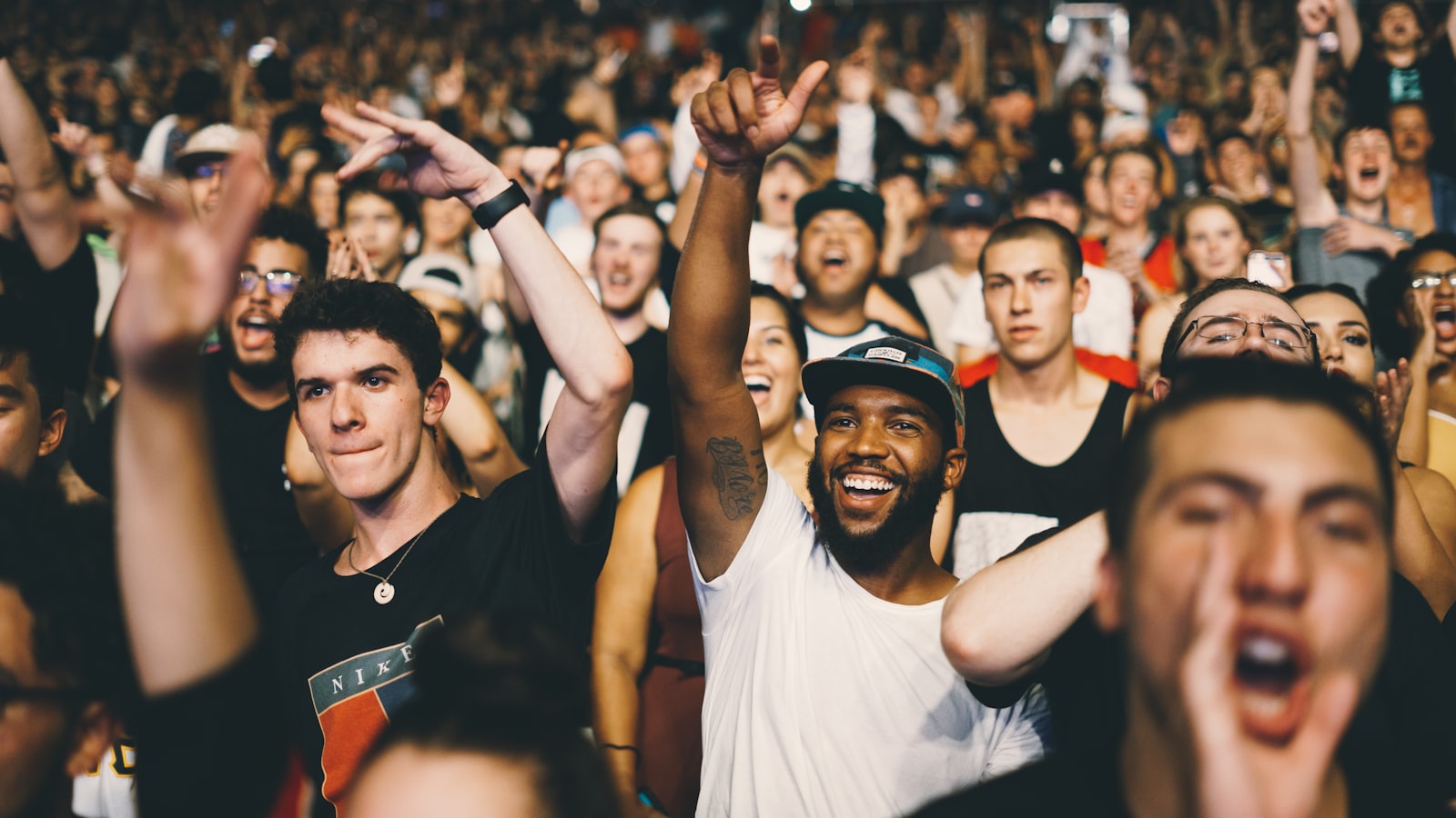 A crowd at a live music show with hands raised towards the stage