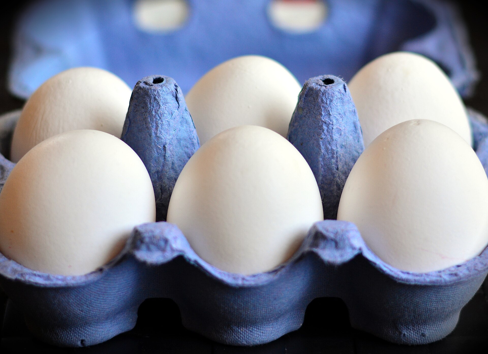 Half a dozen white eggs in a blue cardboard box - egg yolks carry vitamin D, but nowhere near enough to cover a British winter