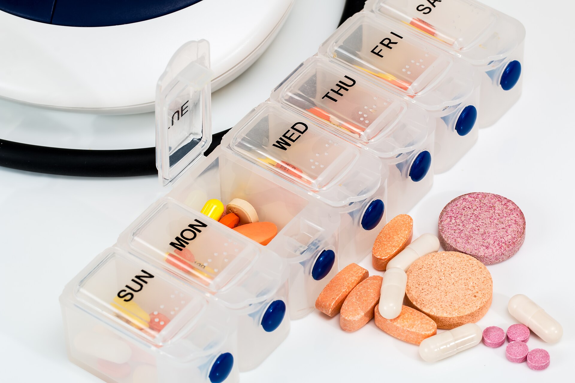 A weekly pill organiser spilling over with colourful tablets and capsules