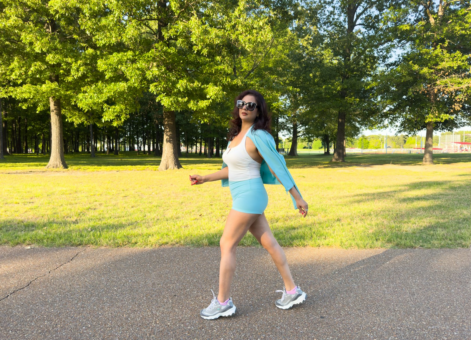 Woman walking a paved park path - weighted vest walking has turned everyday park loops into loaded workouts