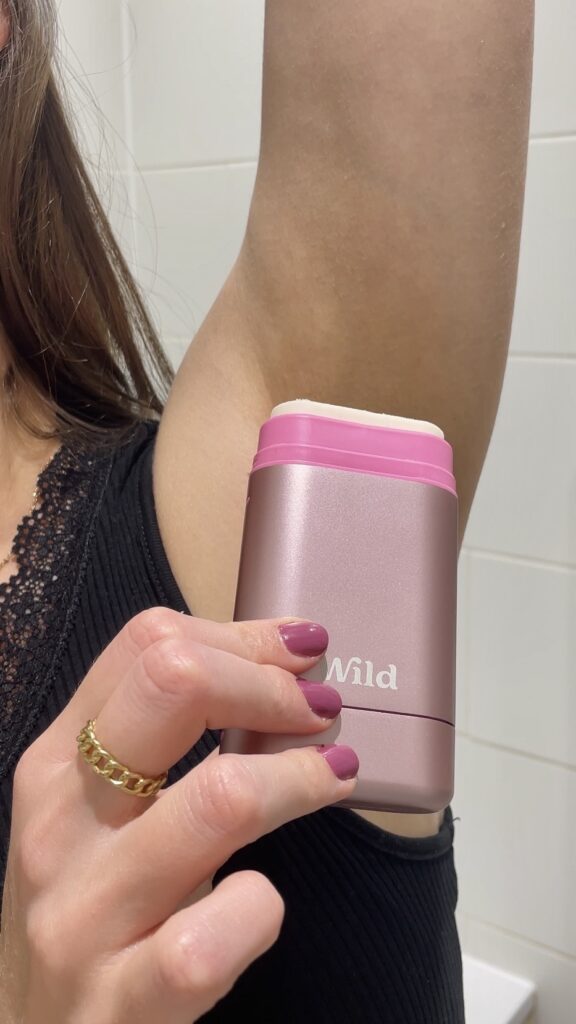applying Wild natural deodorant stick to underarm