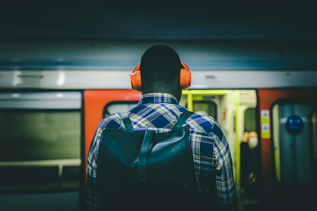 Commuter wearing headphones waiting on a London Underground platform as a train arrives
