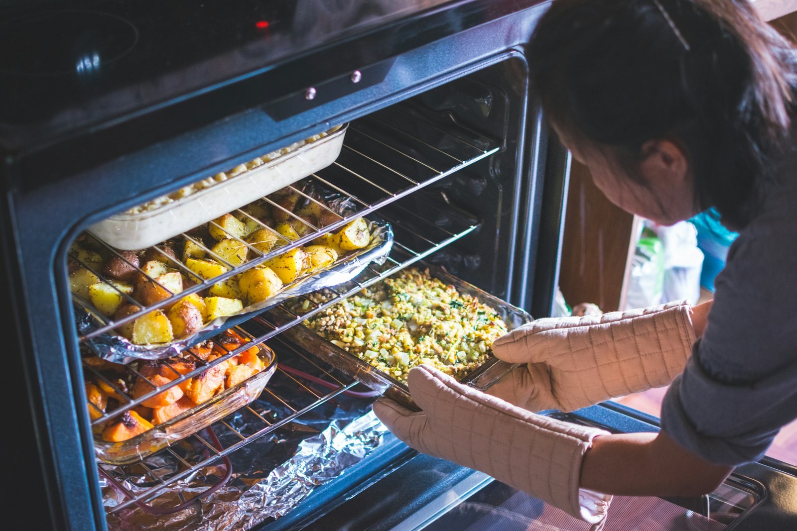 A full-size oven being loaded with several trays at once - the point where the oven becomes cheaper per portion than an air fryer