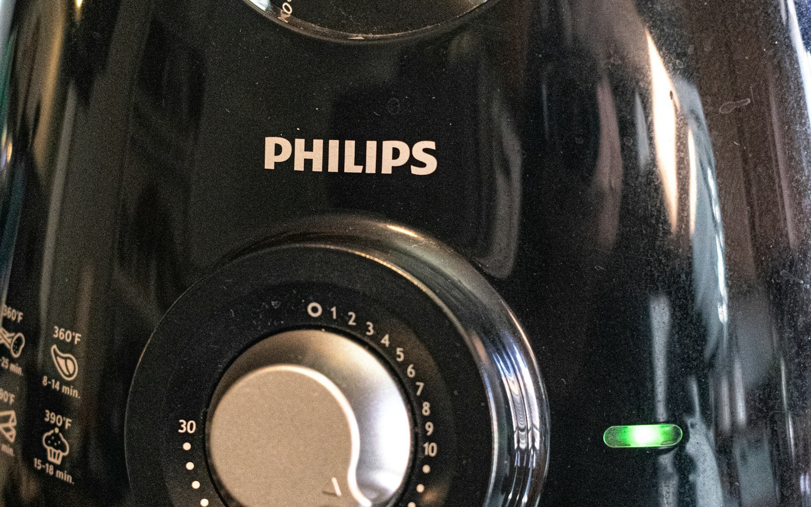 Close-up of a black air fryer's control dial and indicator light