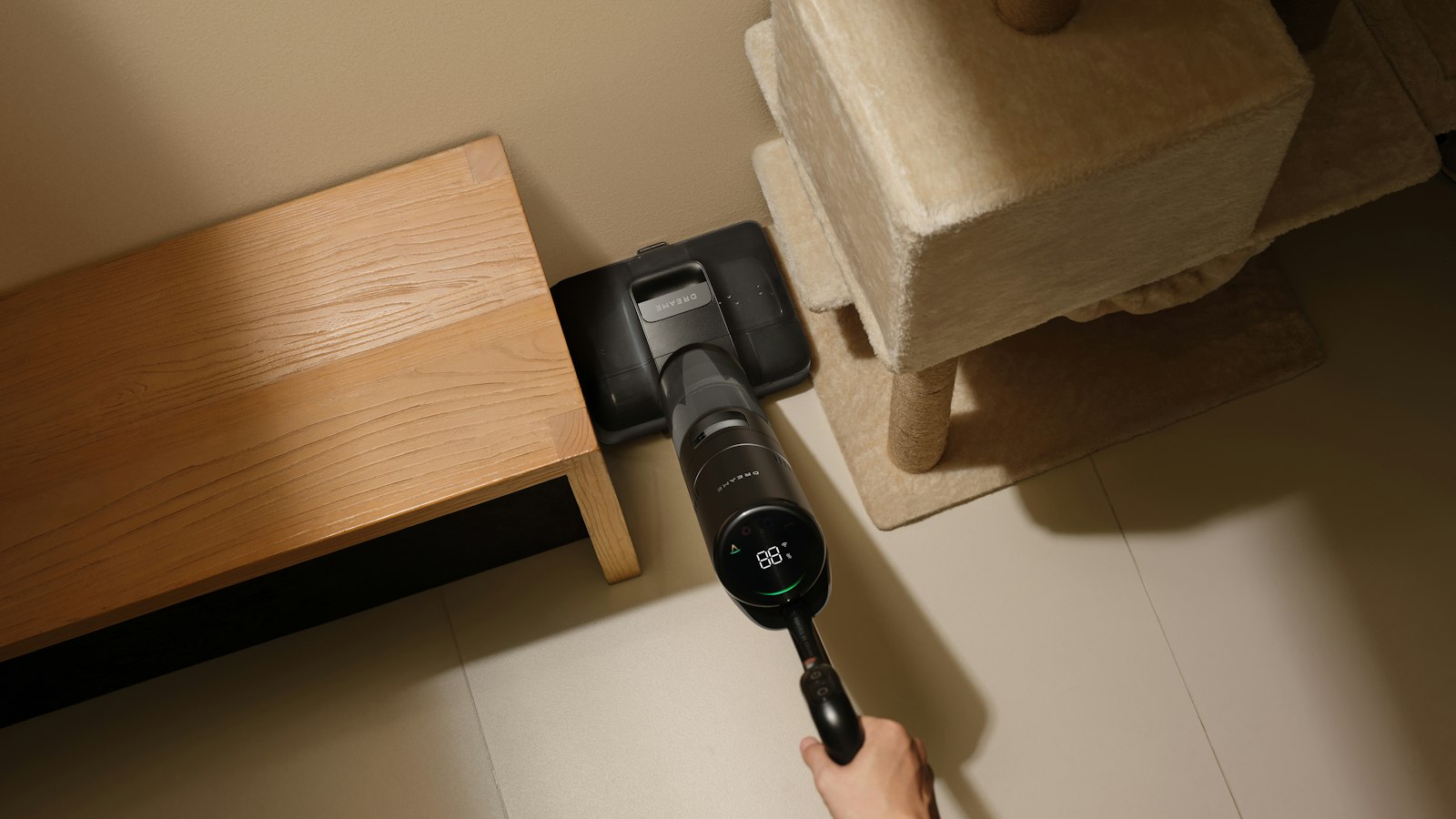 Person cleaning a corner of the room with a cordless stick vacuum