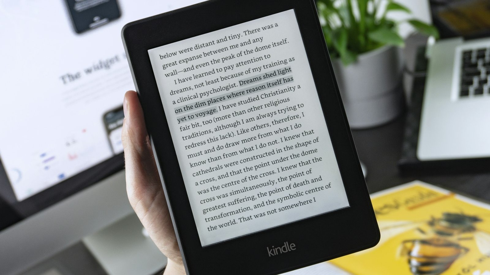A hand holding a Kindle with highlighted text, the front-lit screen that makes an e-reader under £100 useful after dark