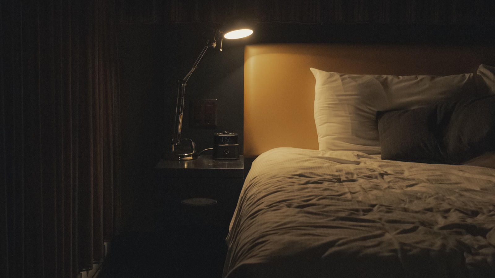 Bedside lamp on beside a made bed, the bed an electric blanket warms for 2p an hour
