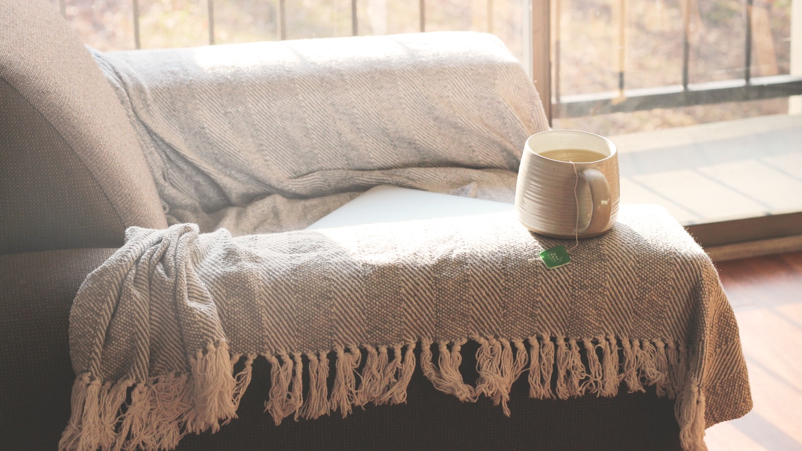 Coffee cup on a sofa by the window, the spot where a heated throw earns its keep on autumn evenings