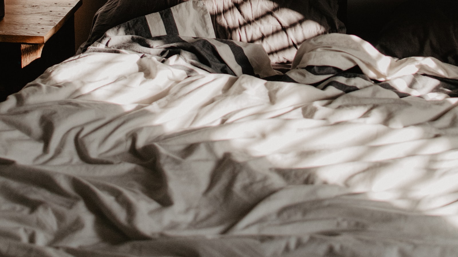 Rumpled bed with striped bedding, the kind of bed the best electric blanket 2026 warms in five minutes