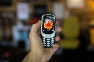 Child's hand holding a basic Nokia brick phone - the best first phone for kids in 2026