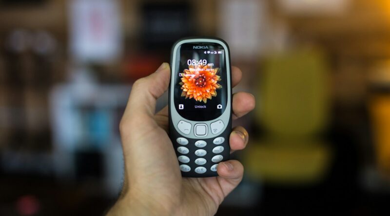Child's hand holding a basic Nokia brick phone - the best first phone for kids in 2026
