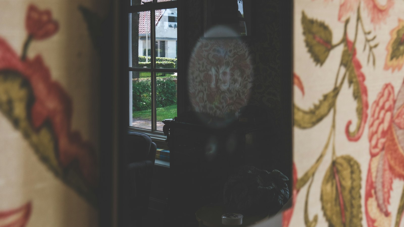 Black digital thermostat mounted on a floral wallpapered wall in a UK home