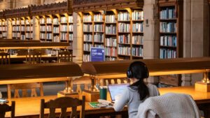 A student studying at a laptop in a large old university library - choosing the best student laptop under £500 for freshers 2026