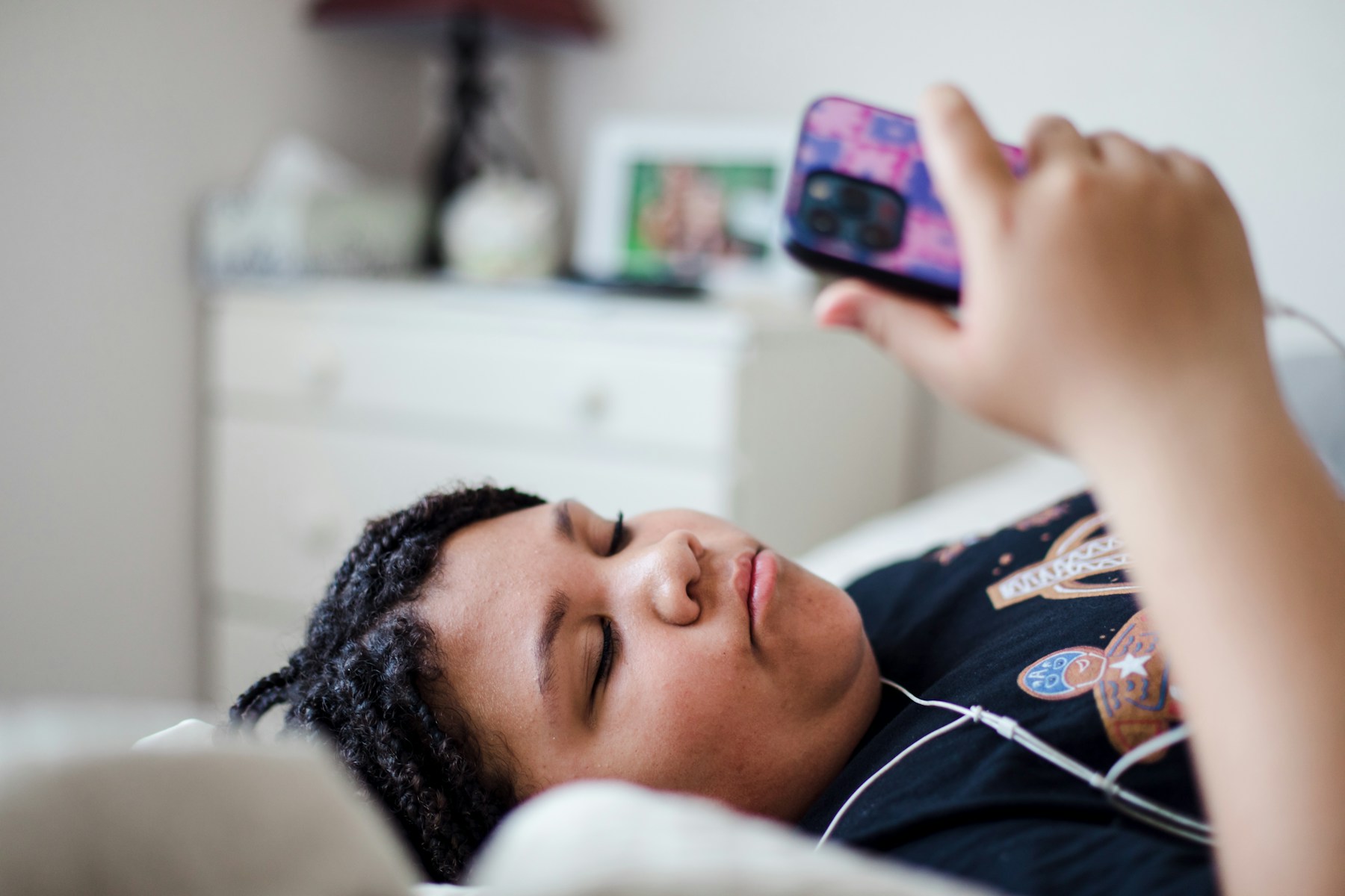 Woman lying in bed looking at her phone at night, the habit blue light glasses claim to fix